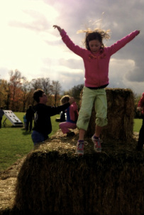 Girl jumping off hay bale